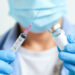 doctor's hand holds a syringe and a blue vaccine bottle at the hospital. Health and medical concepts.